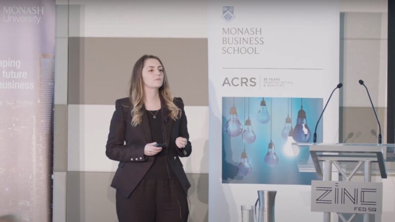 Woman presenting to group from stage for Monash Business School