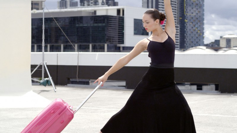 woman dancing with pink suitcase