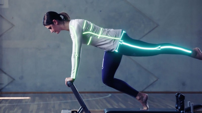 female athlete on reformer bed stretching in active wear. Light animation highlighting her bone structure